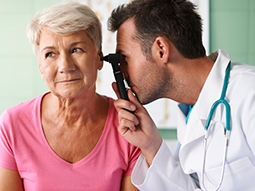 Otolaryngologist examining ears with ENT tuning fork of young patient