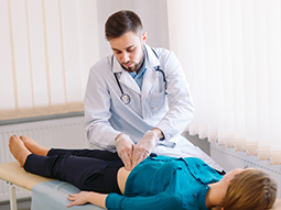 Hernia specialist examines the stomach of the patient on the table