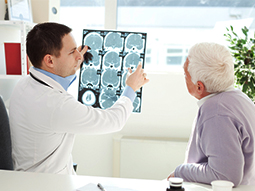 Neurosurgeon examining x-ray scans of senior patient