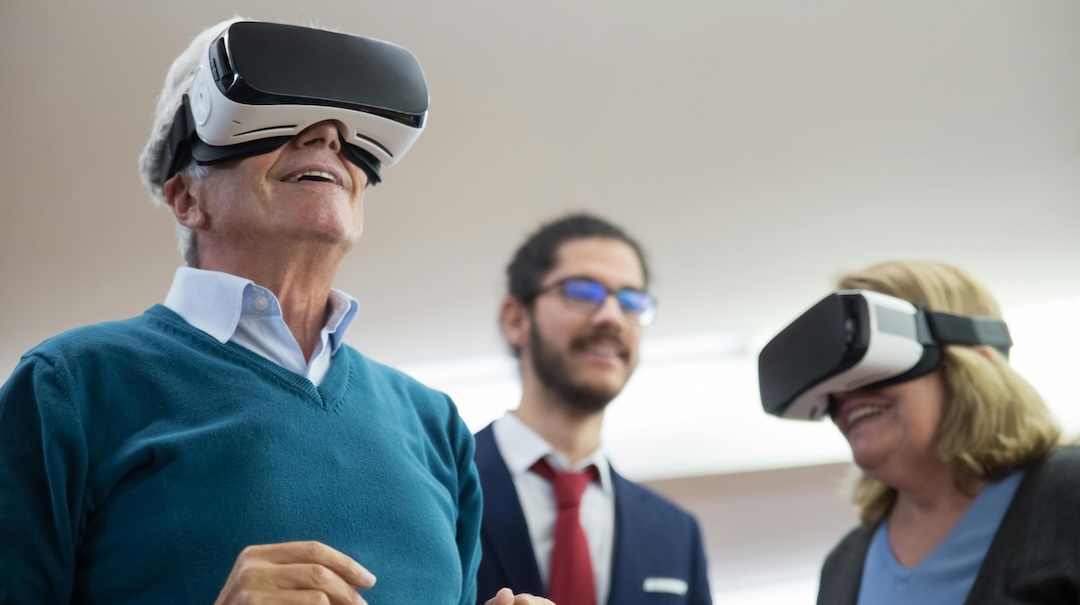 Older adults smile while experiencing virtual reality goggles.